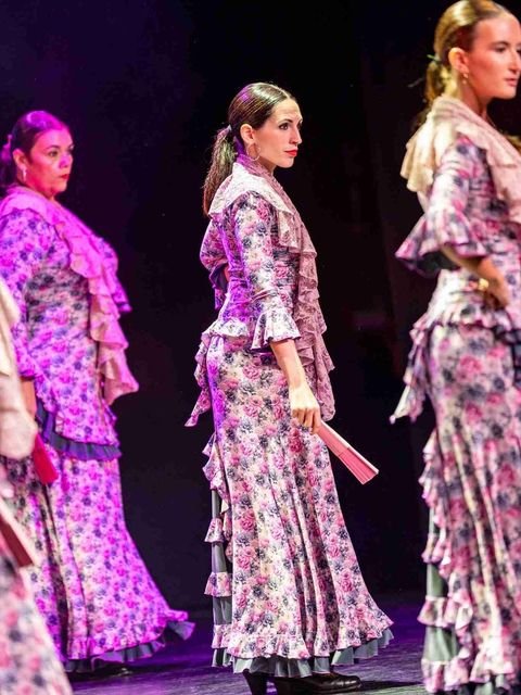 Tres alumnas de la escuela con trajes de flamenca floreados durante una actuación